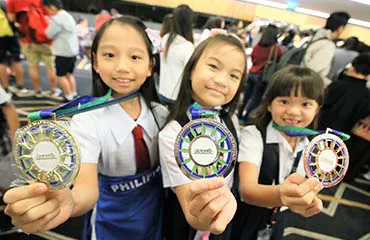 girls winning medals after attending math olympiad training in Singapore